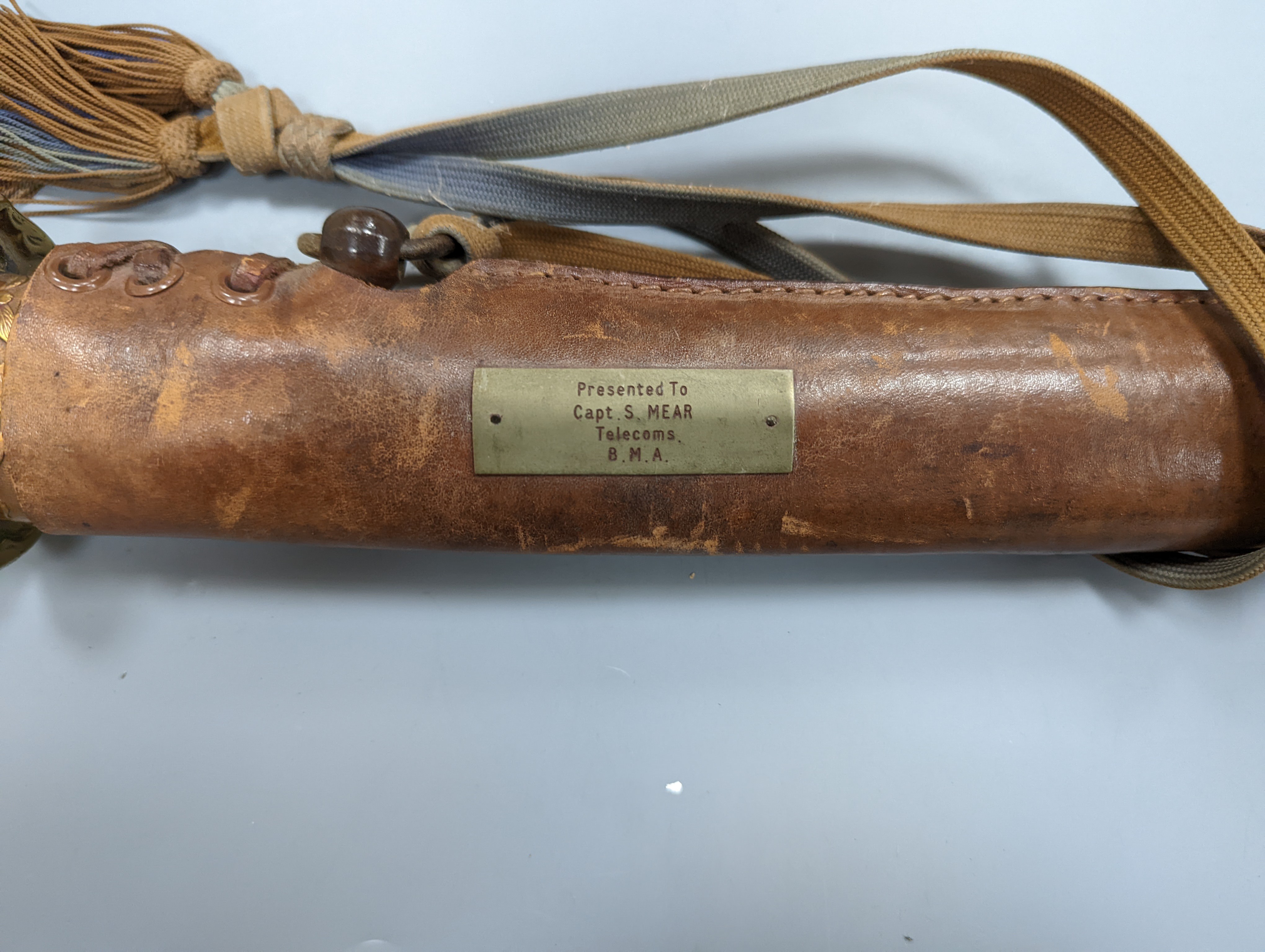 A Japanese Katana with leather covered sheath, plaque reading ‘Presented to Capt. S. Mear Telecoms B.M.A’ 93 cms long.